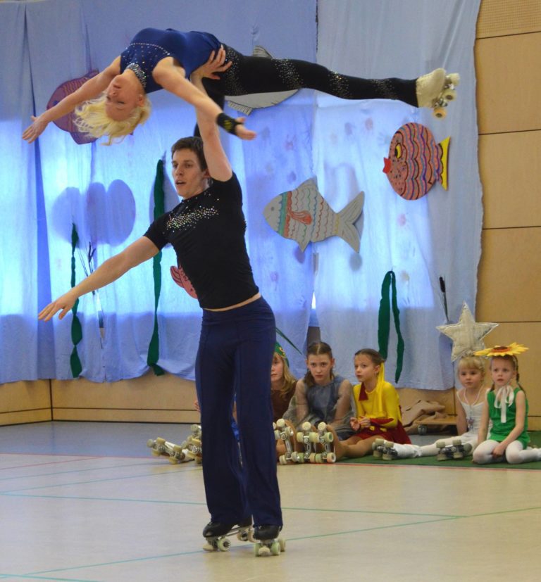 Mit Herz und sportlichem Ehrgeiz - Rollkunstlaufpaar - Er hält sie mit einem Arm oben schwebend in der Luft